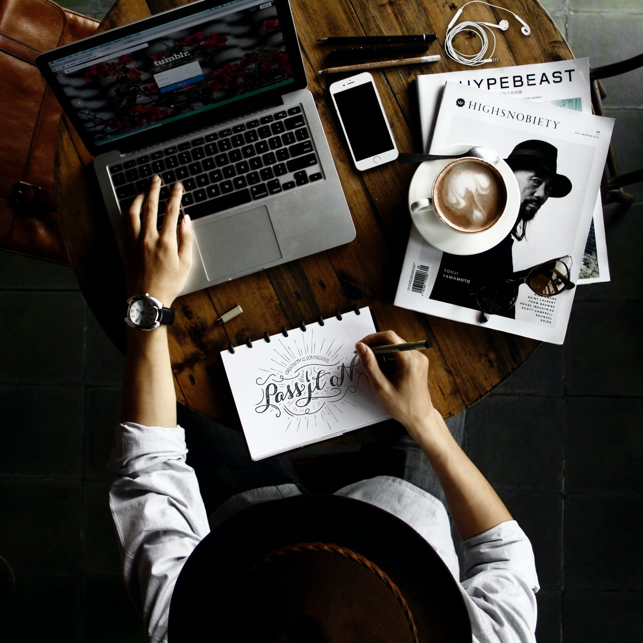 Hipster designer working at desk with laptop and drawings