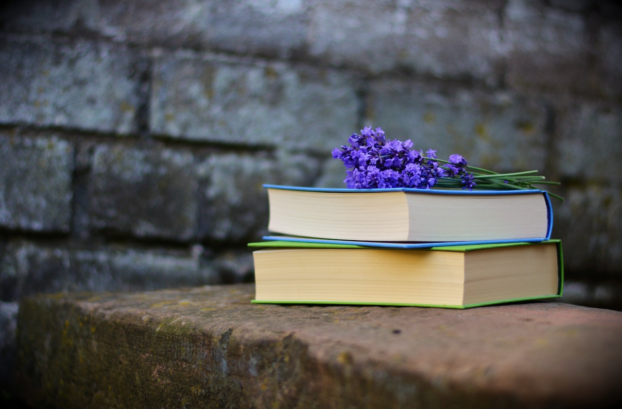 purple flowers on stack of books