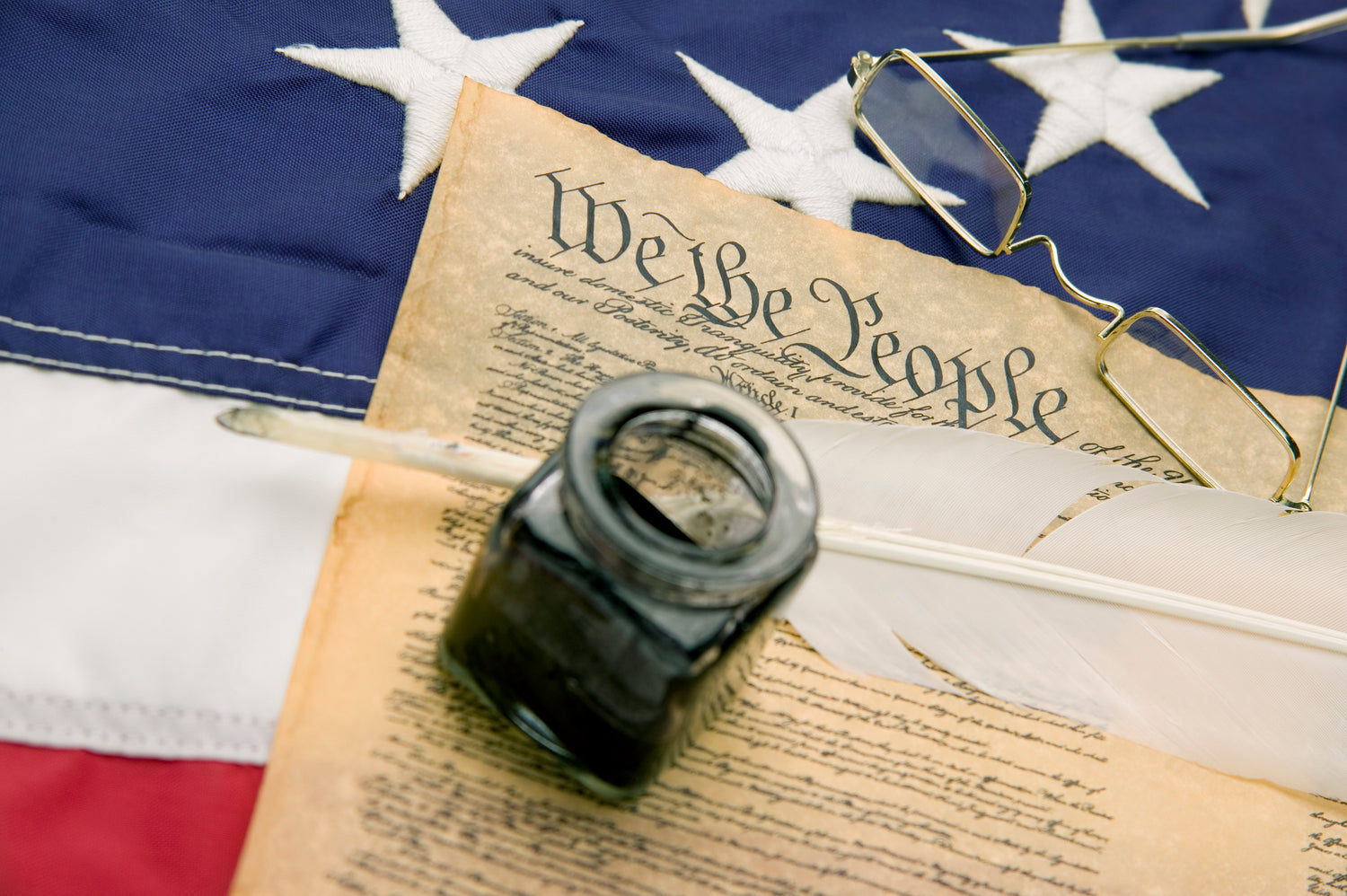US Constitution with quill, inkwell and flag