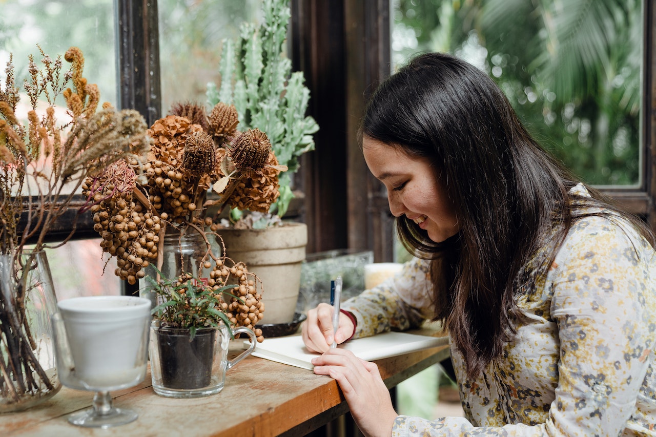 Lady writing at rustic desk with dried flowers