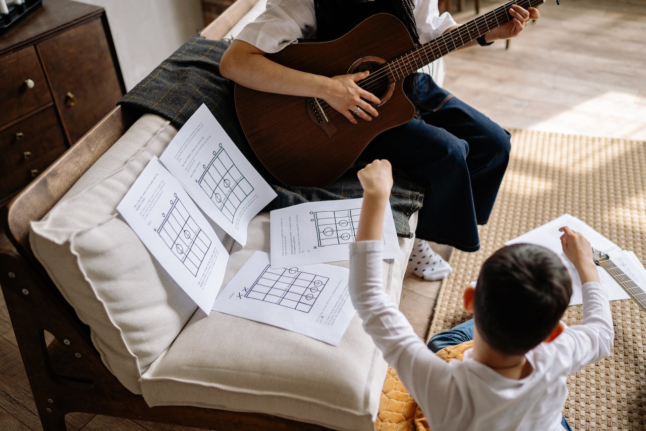 teacher with student and sheet music playing guitar